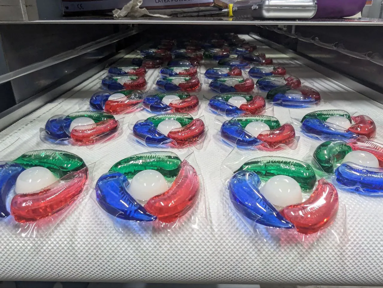 Mass production of finished laundry pods on a conveyor at our household chemicals manufacturing facility